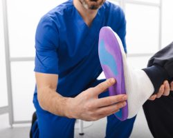 Orthopedist fitting individual orthopedic insole for patient foot. Orthopedic insoles